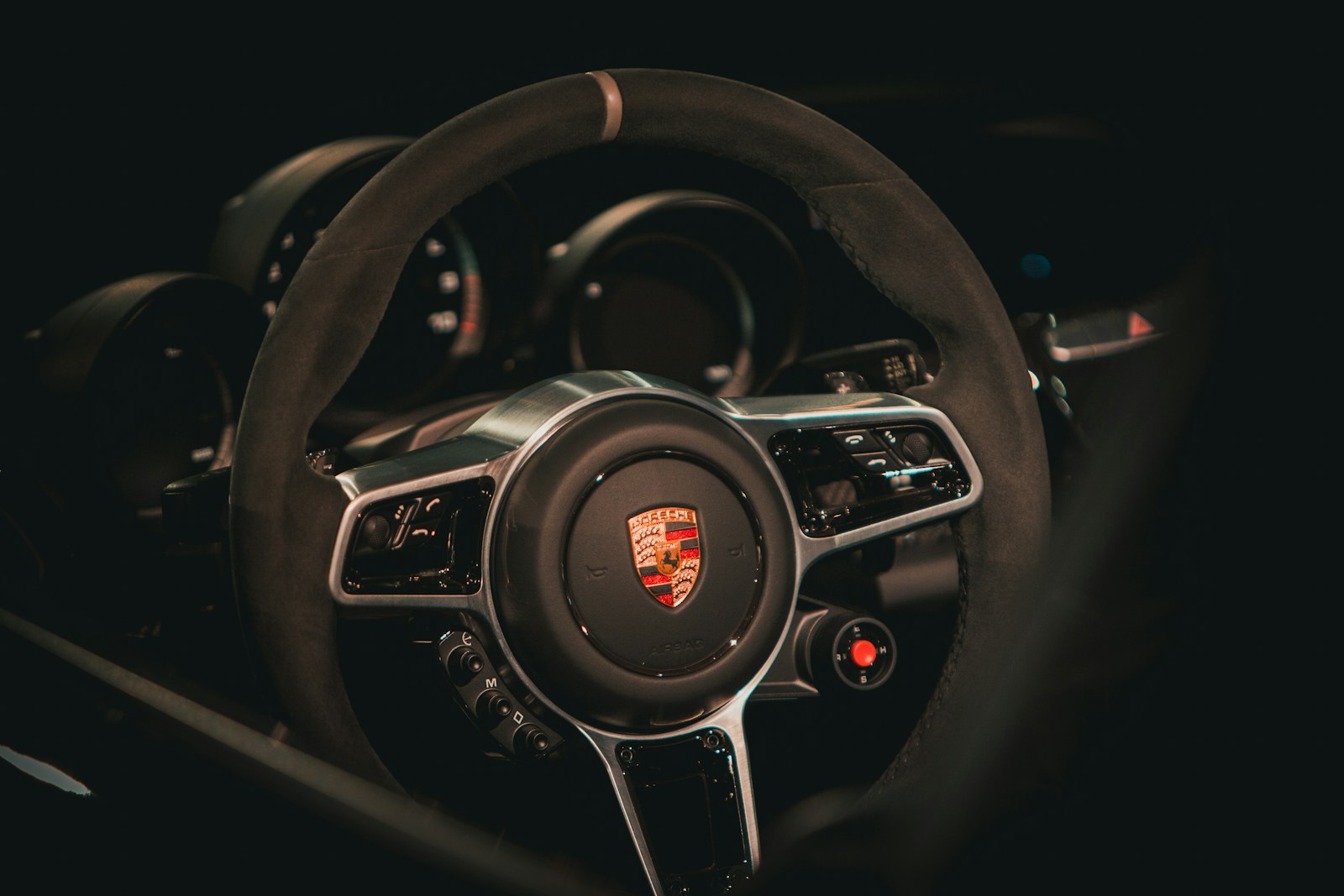Dettaglio del volante e della strumentazione di una Porsche, in un abitacolo scuro